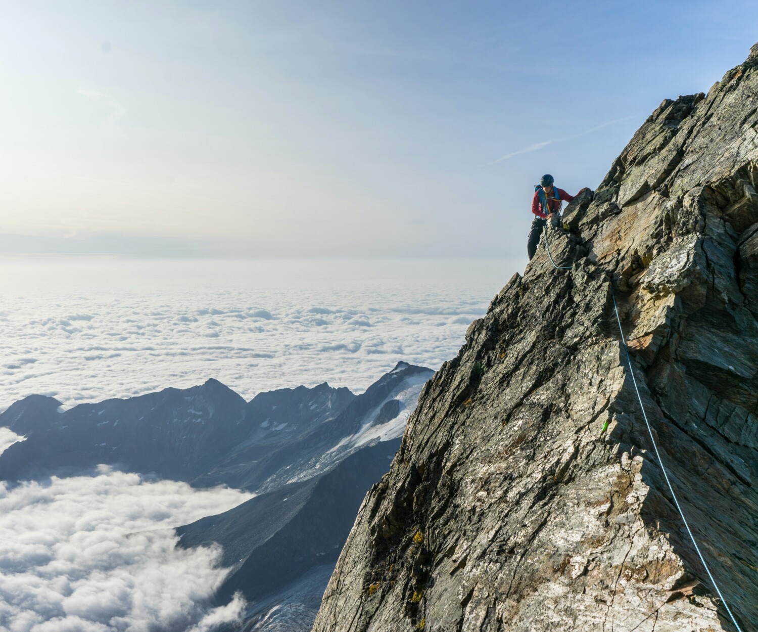 Man climbing face of mountain with a rope