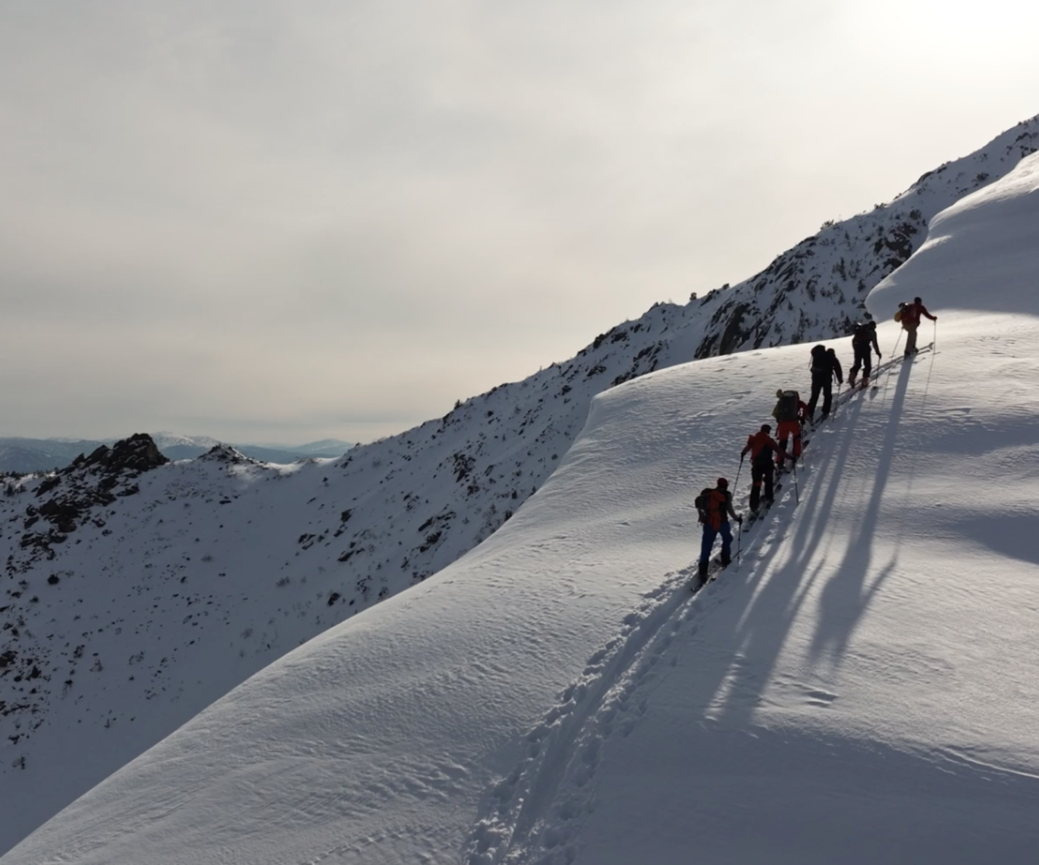 Men trekking in the snow on skis up a mountain