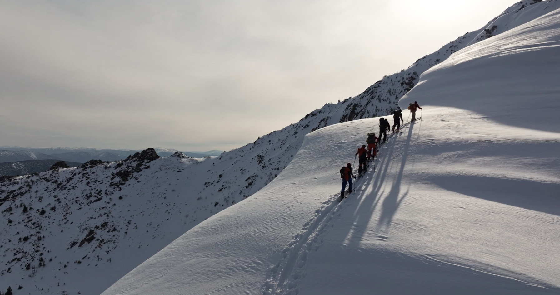 Men trekking in the snow on skis up a mountain
