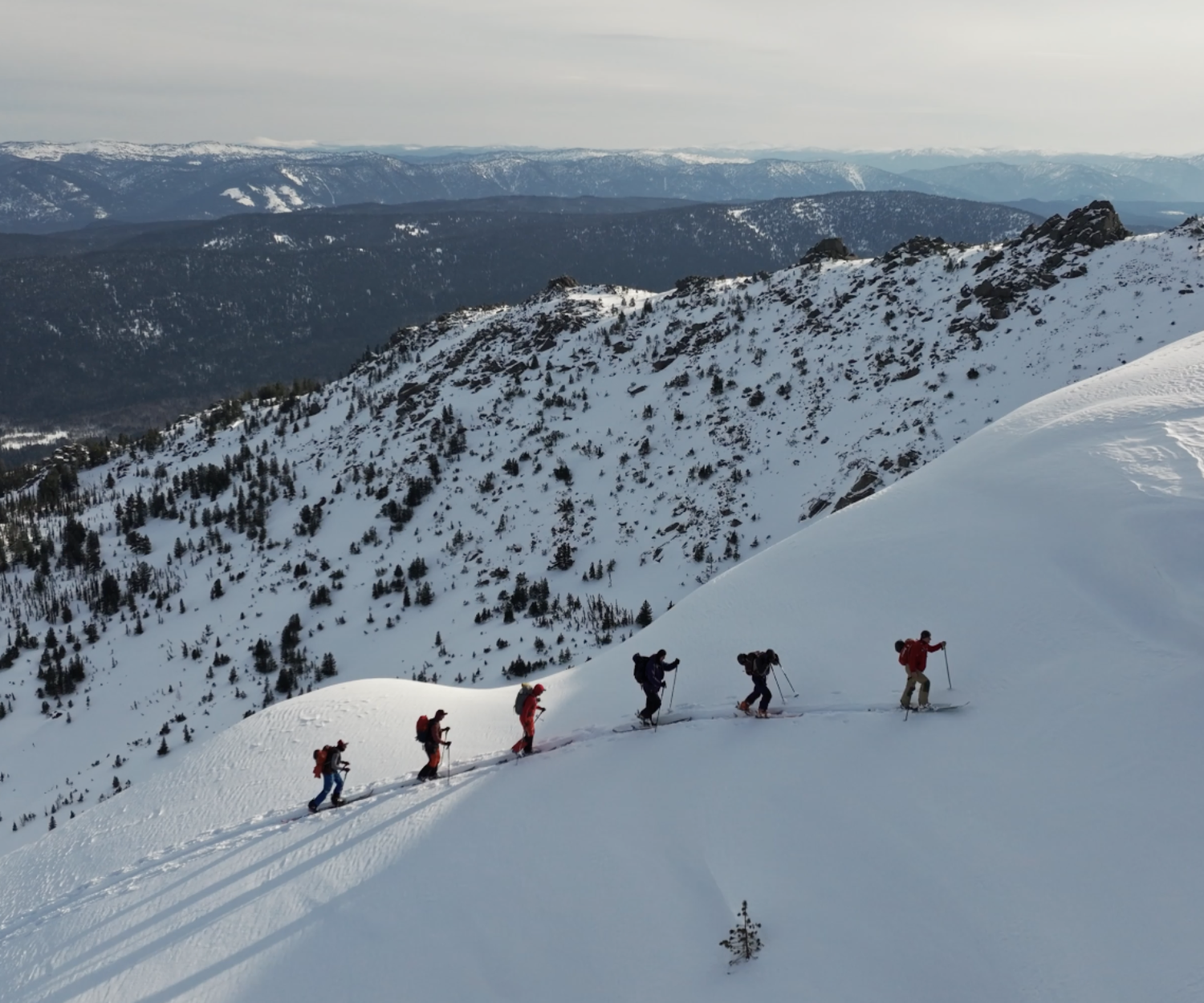 Men trekking in the snow on skis with a mountain range background